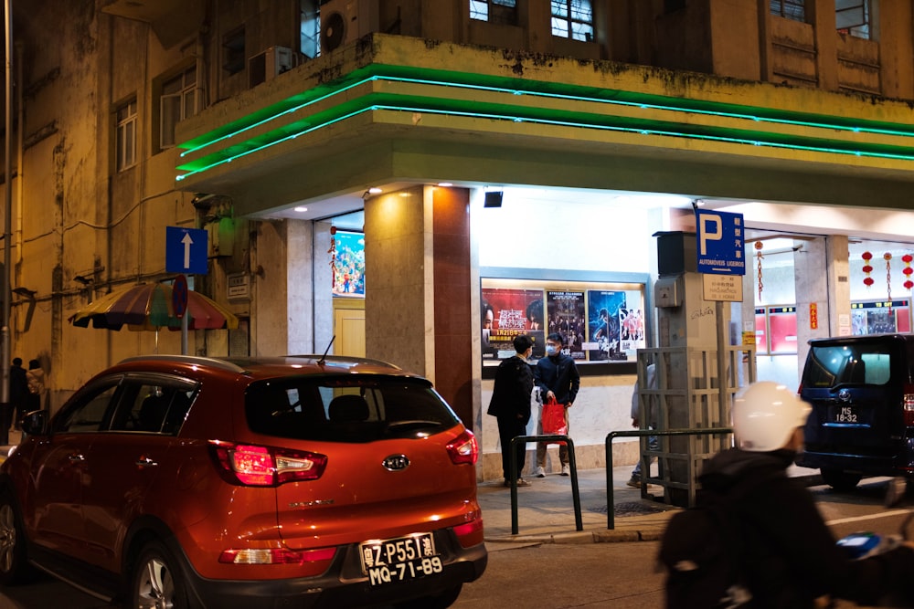 a red car parked in front of a gas station