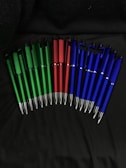 A collection of personalized pens decorated with vivid green and red details on a white surface.