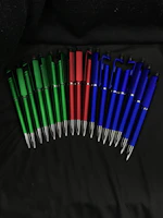 A collection of ballpoint pens in various colors laid out on a wooden desk.