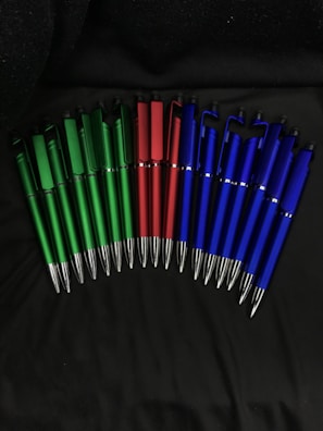A collection of personalized pens decorated with vivid green and red details on a white surface.