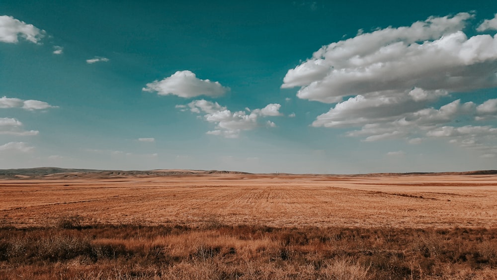 a large open field with a few clouds in the sky