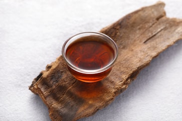 a glass of tea sitting on top of a piece of wood