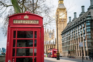A cozy London street scene with classic red phone booths and a glimpse of the Thames River in the background.