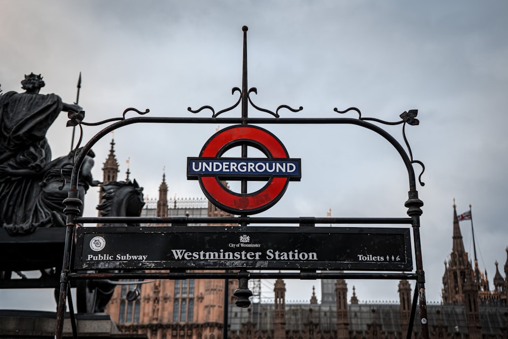 a red and black sign and some buildings and clouds