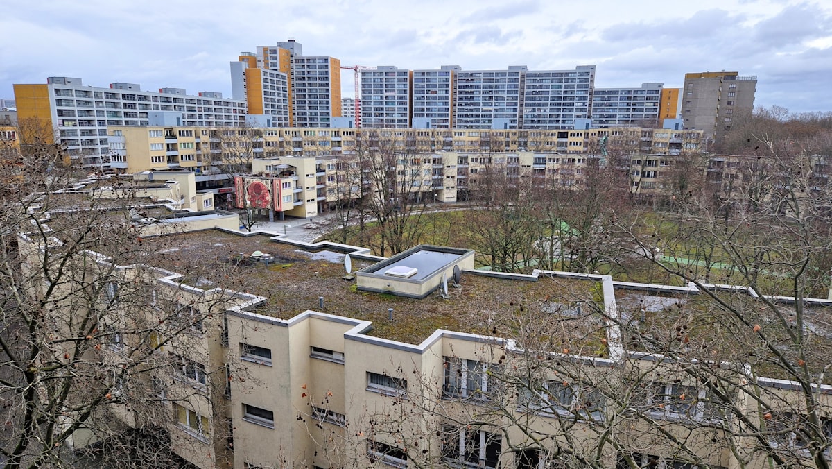 A vegetated green roof on an urban apartment block, with residential blocks and trees behind