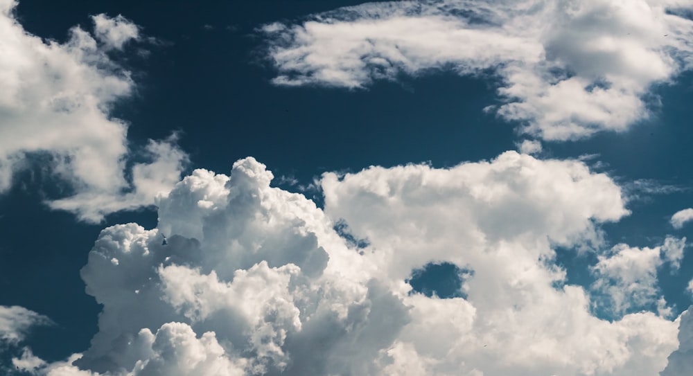 a plane flying through a cloudy blue sky