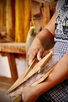 Artisan hands shaping wool fibers over a wooden table bathed in natural light.