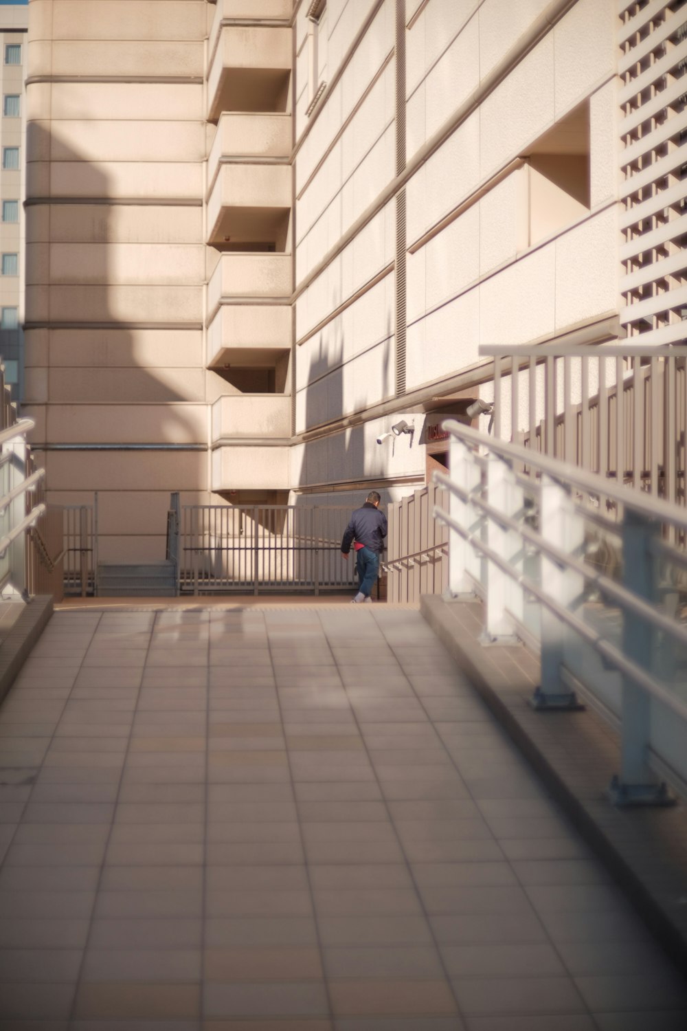 a person walking down a walkway next to a tall building