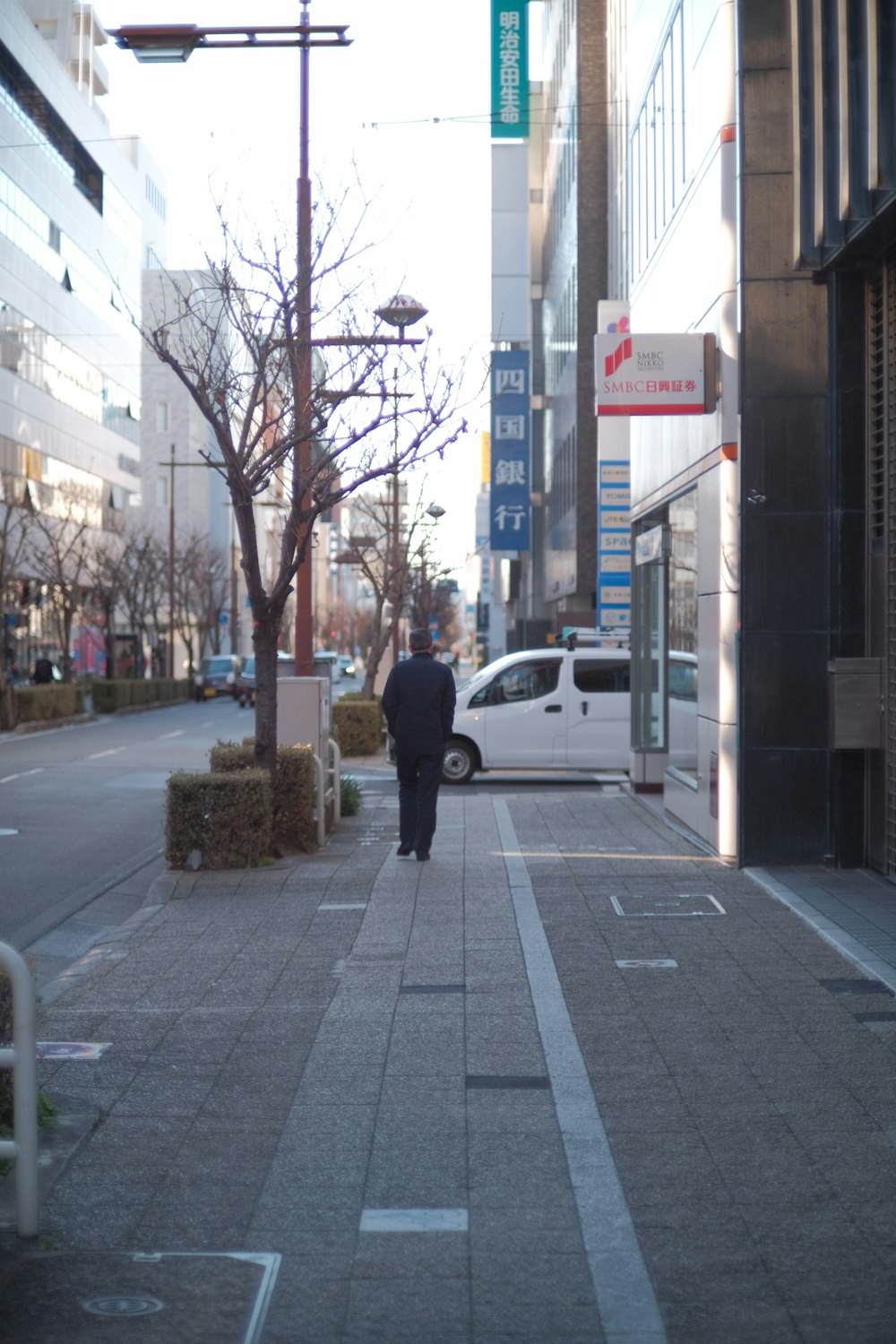 a man walking down a sidewalk next to a white van