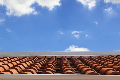 View of a team repairing a tiled roof under a bright blue sky in a residential area.