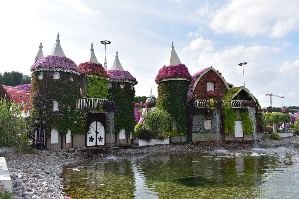 a group of houses covered in flowers next to a body of water