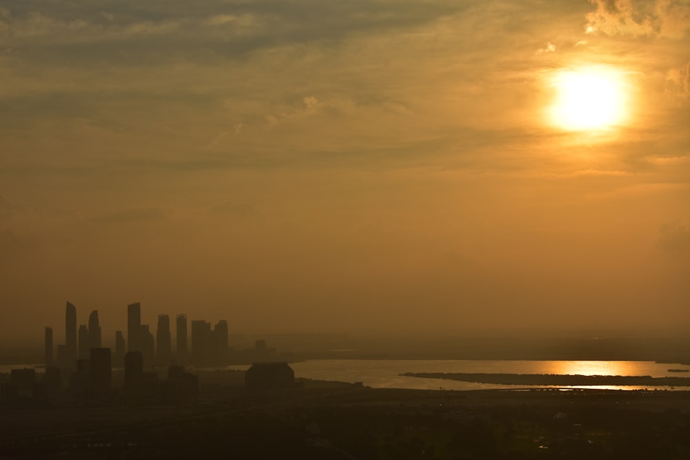 the sun is setting over a city and a body of water