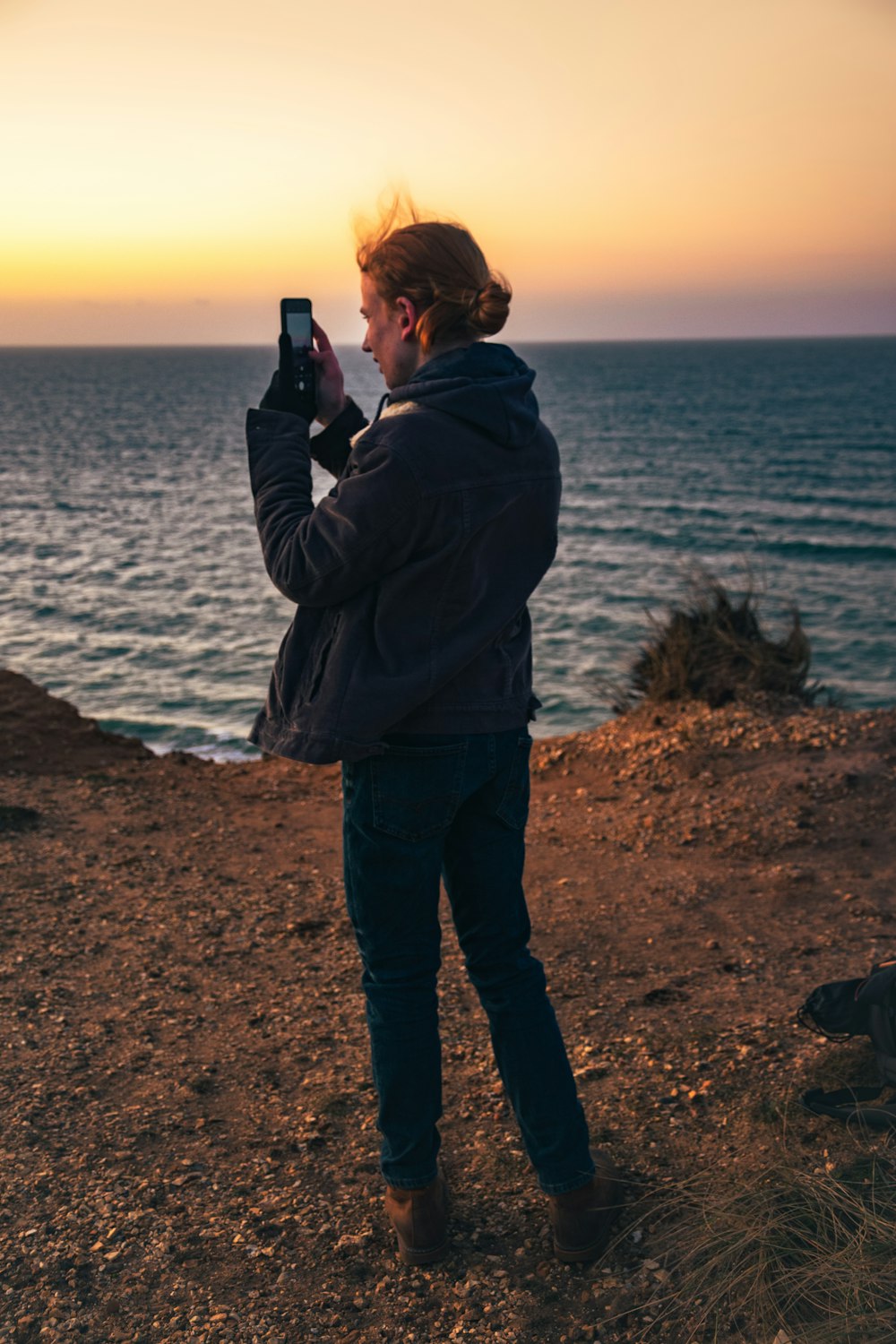 Un homme prenant une photo de l’océan avec son téléphone portable