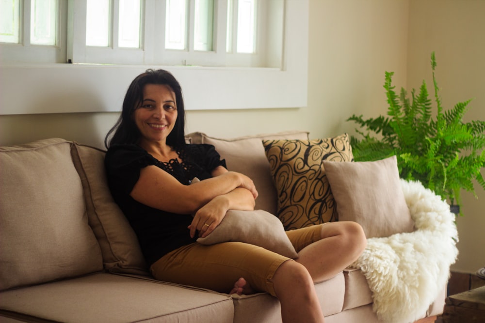 Une femme assise sur un canapé, les jambes croisées