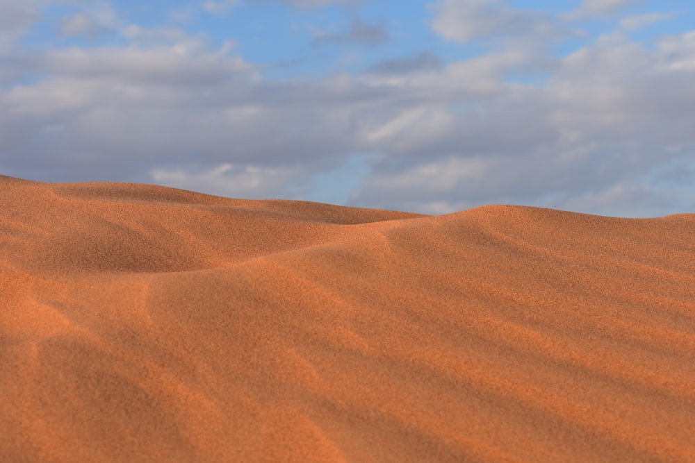 a sandy area with a few clouds in the sky