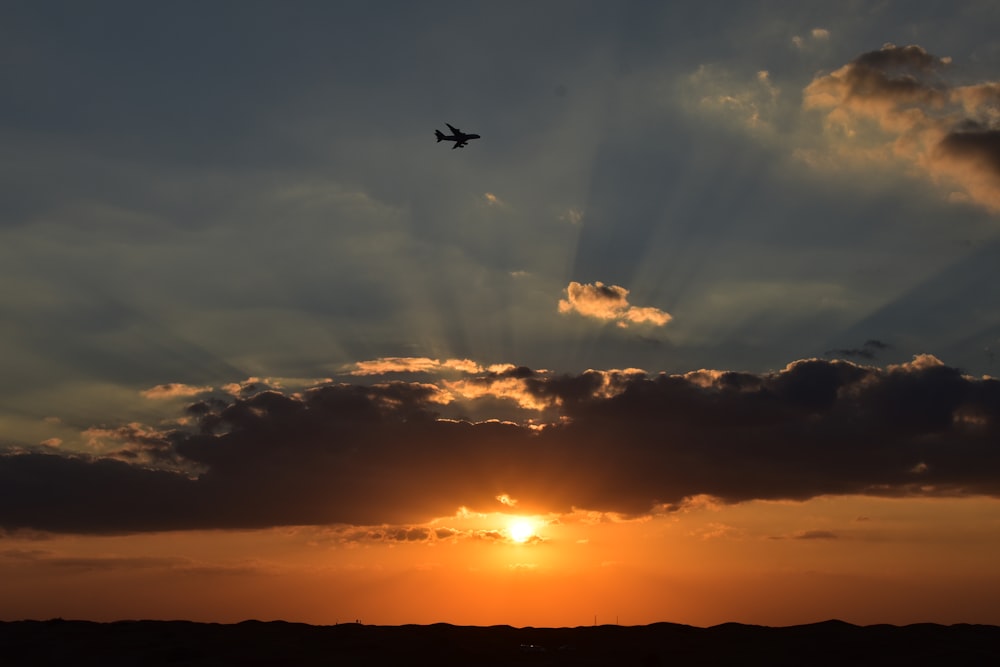 a plane flying in the sky at sunset