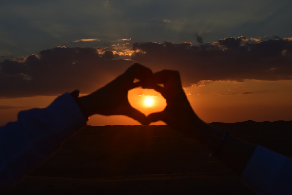 a person making a heart shape with their hands