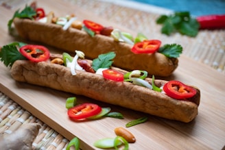 two hot dogs with toppings on a cutting board