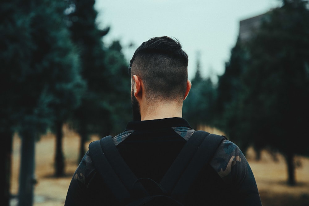a man with a back pack walking through a park