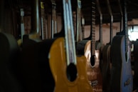 A row of guitars hanging on a wooden wall inside a warmly lit store