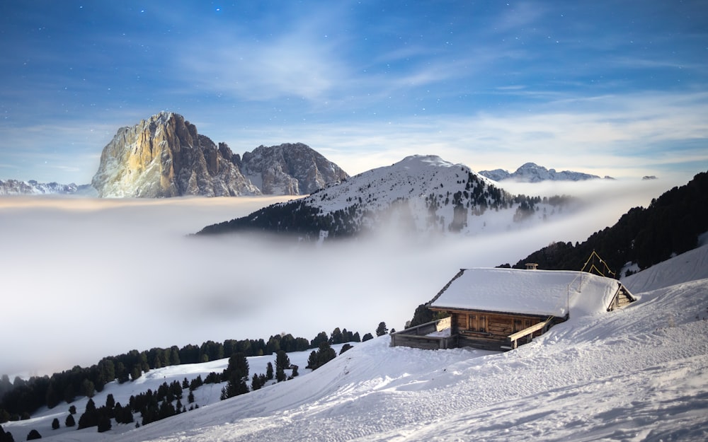 a snowy mountain with a cabin in the foreground