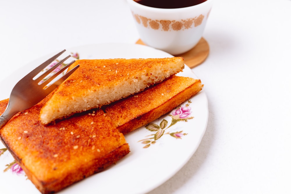 a white plate topped with french toast next to a cup of coffee