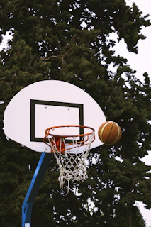 A close-up of a basketball hoop with a ball about to go through the net during a game.