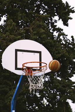 A close-up of a basketball hoop with a ball about to go through the net during a game.