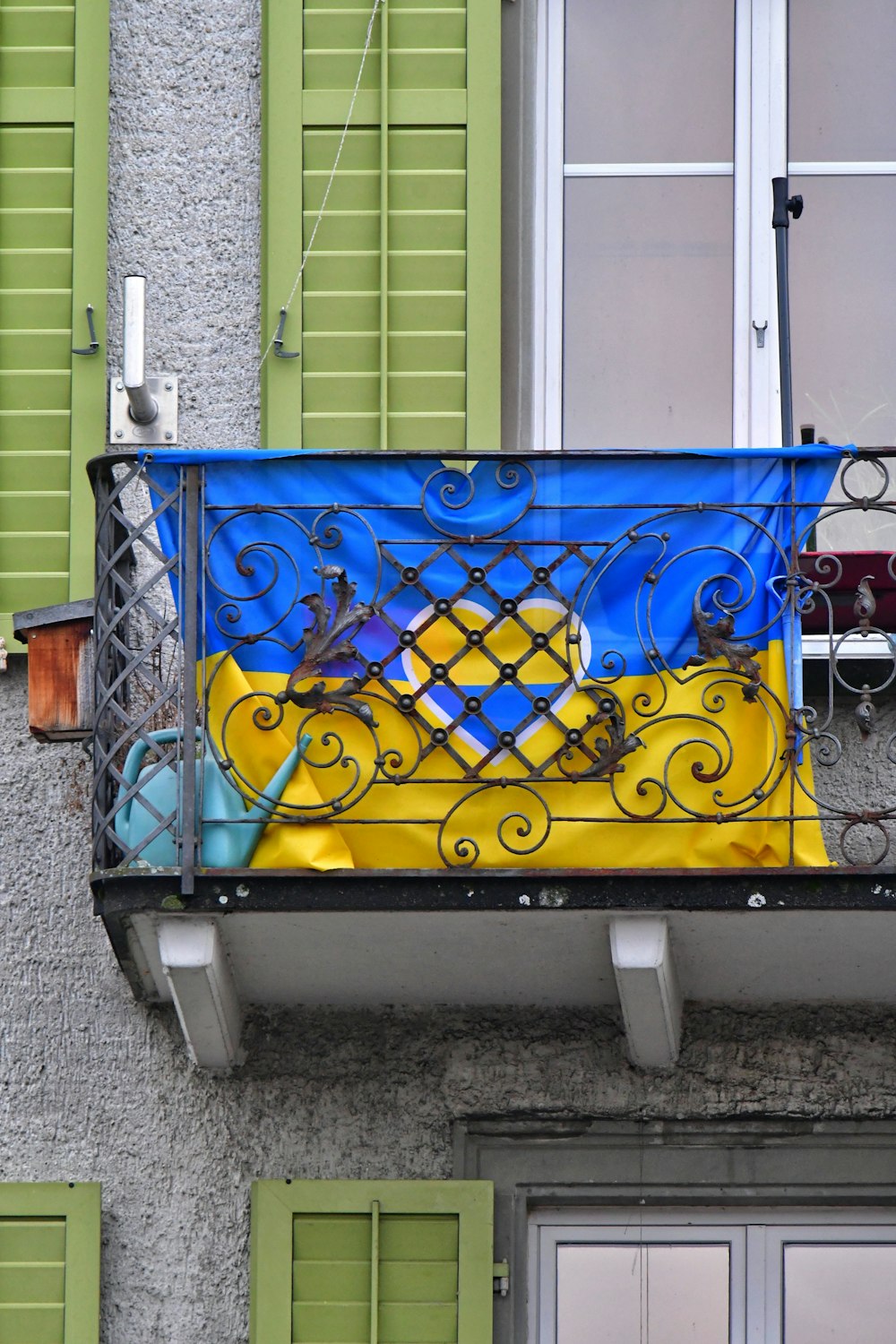 un balcon avec volets verts et un balcon peint en bleu et jaune