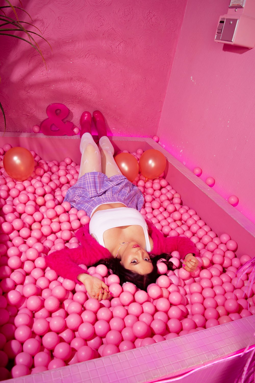 a woman laying on top of a pink ball pit