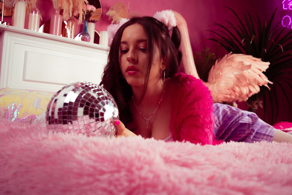 a woman laying on a bed with a disco ball