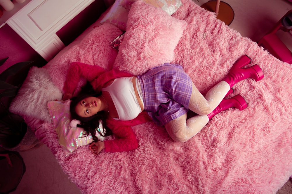 a little girl laying on a pink bed