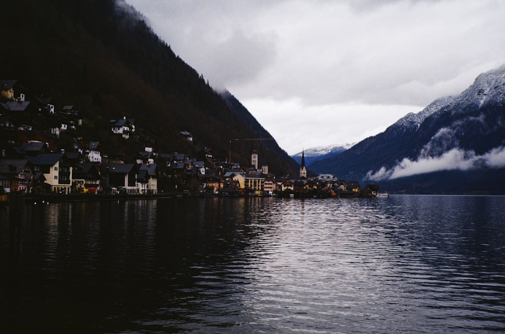 a village on the shore of a lake with mountains in the background