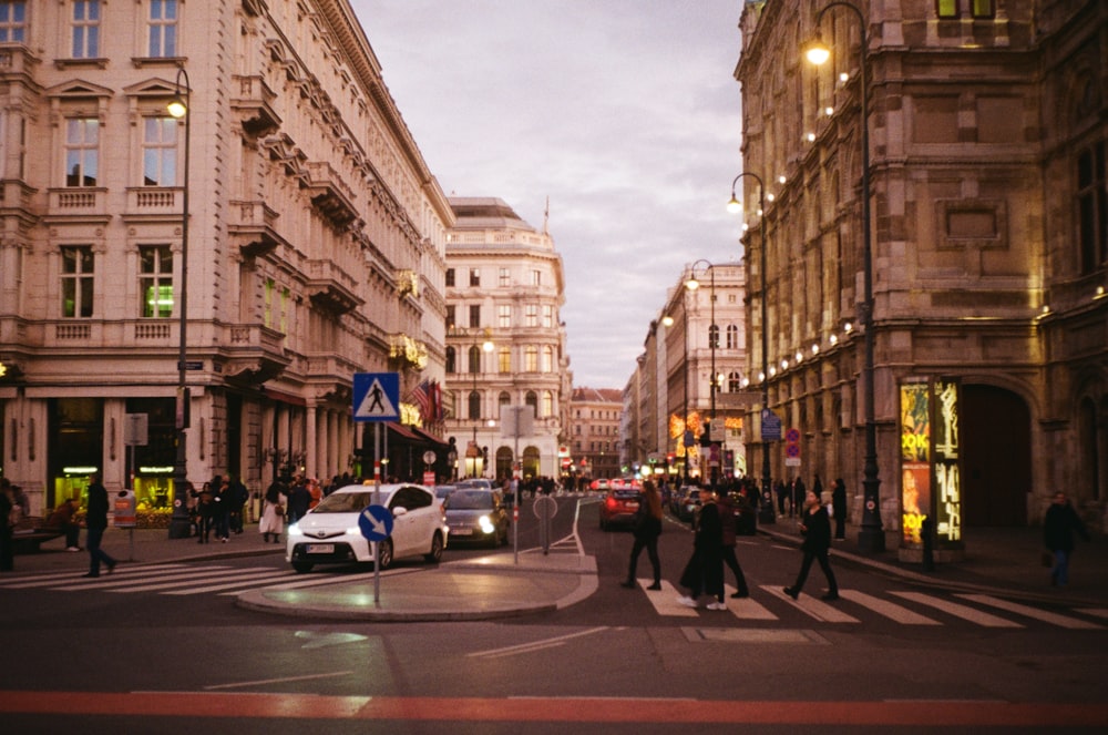 a group of people walking across a street next to tall buildings