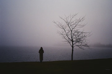 a person standing next to a tree in a field