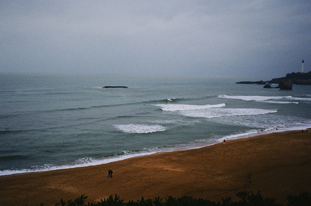 a couple of people standing on top of a sandy beach