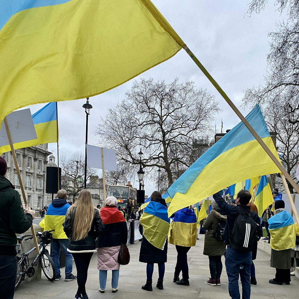 a group of people standing on a sidewalk holding flags