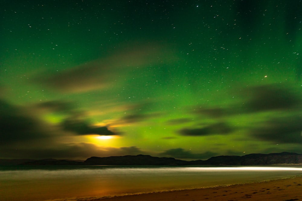 a green and yellow aurora over a body of water