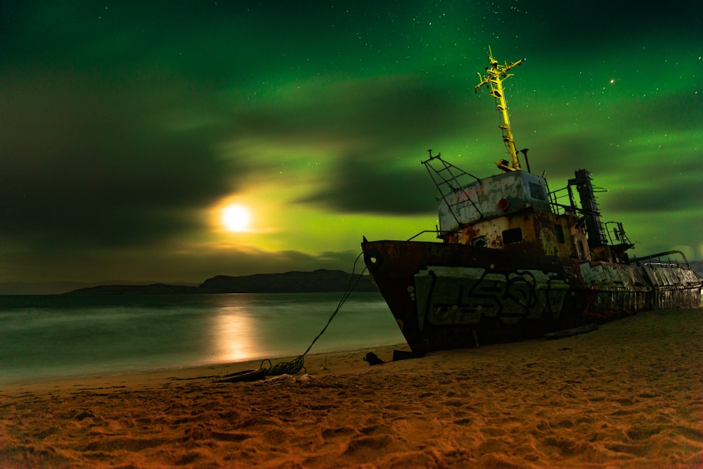 a boat sitting on top of a sandy beach under a green sky
