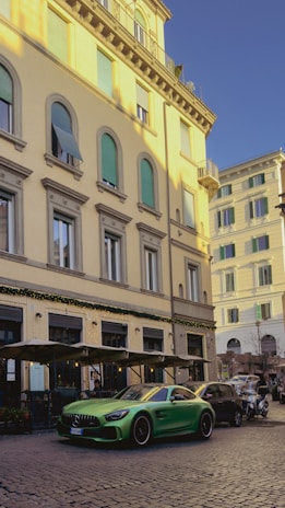 A spacious green monovolume parked near a bustling Italian piazza.