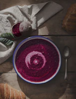 Close-up of a bright beetroot soup topped with a swirl of coconut cream and sprinkled with toasted pumpkin seeds.