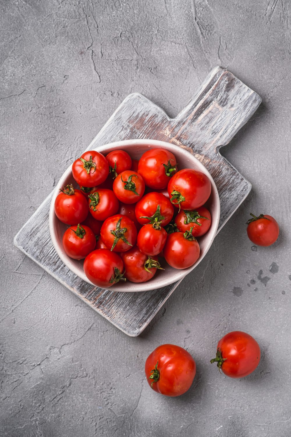 a bowl of tomatoes on a cutting board