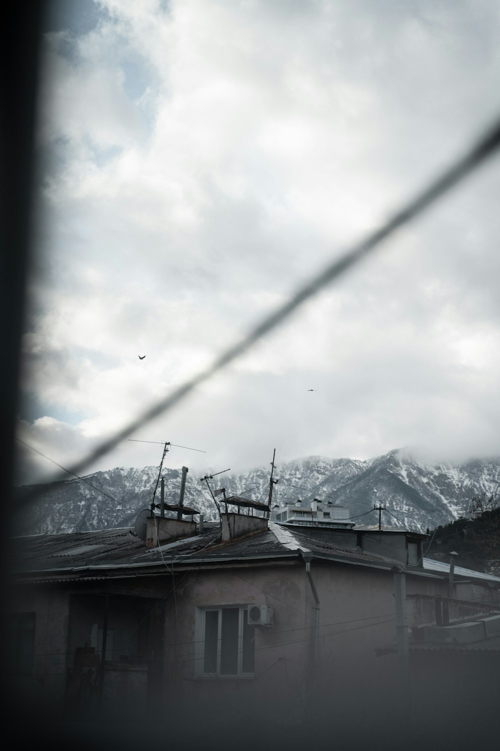 a view of a mountain range through a wire fence