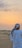 Traveler smiling against a dramatic desert sunset backdrop with dunes in Dubai
