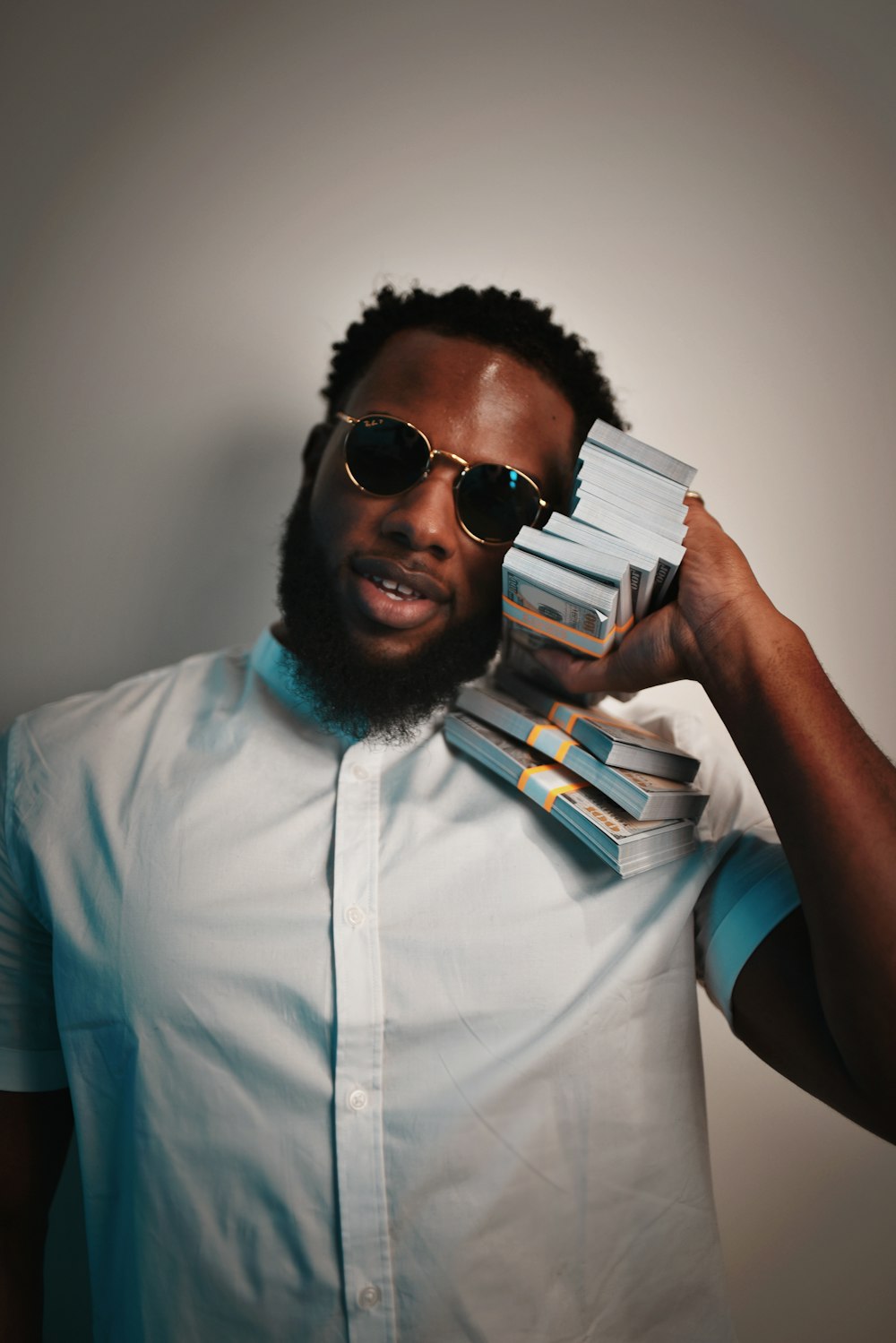 a man wearing sunglasses holding a stack of books