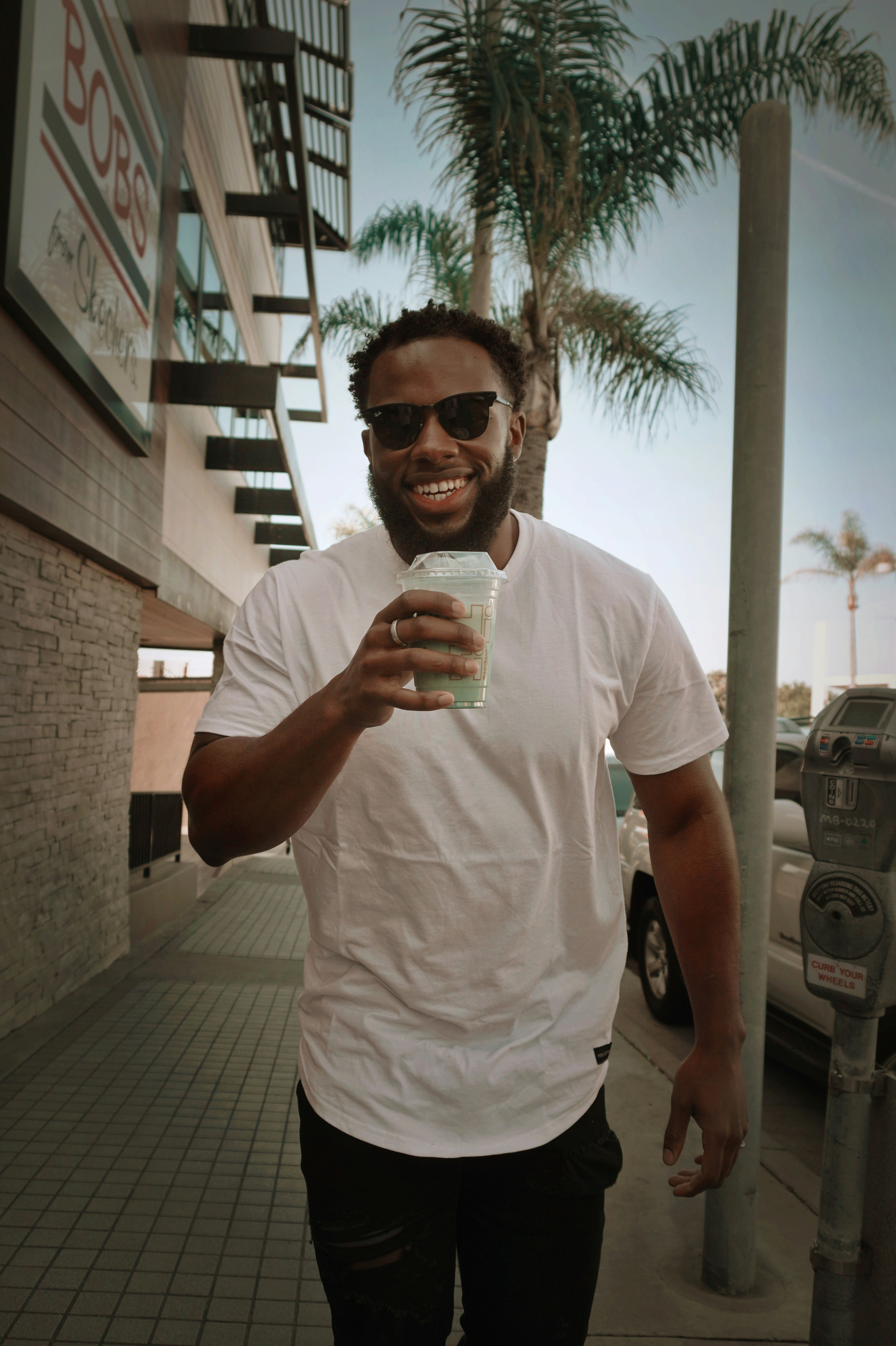 a man standing on a sidewalk holding a cup of coffee