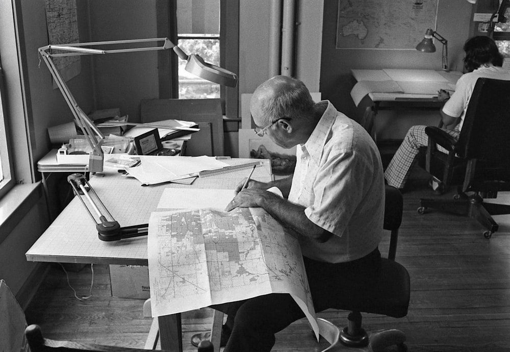 a man sitting at a desk with a map in front of him