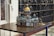 A detailed architectural model of a historic building with a prominent golden dome and intricate design features, displayed on a wooden table. The surrounding area includes marble and ornate carved elements, adding to the sophisticated atmosphere.