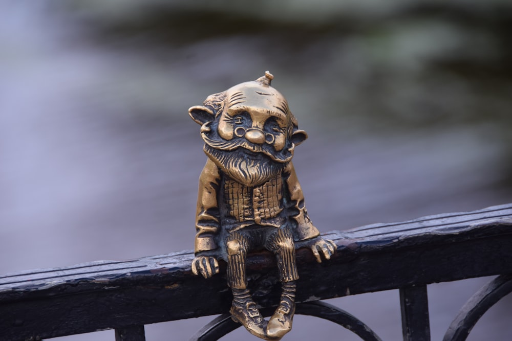 une figurine en bronze posée au sommet d’une clôture métallique