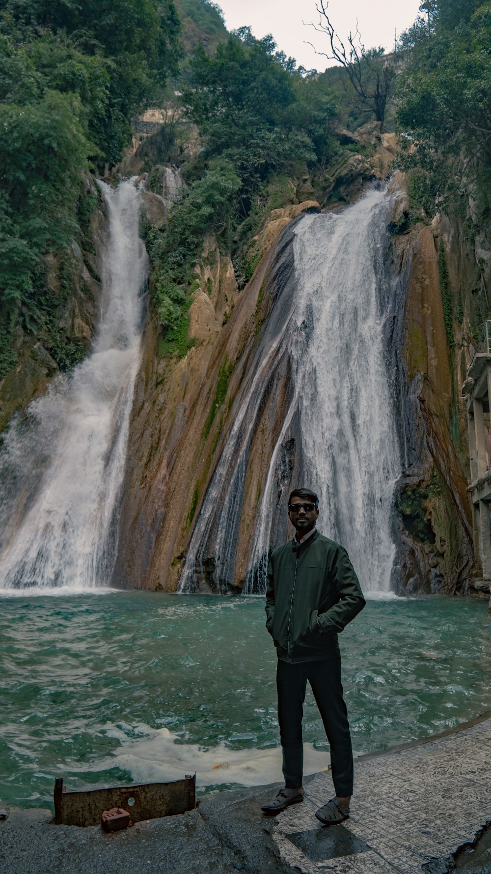 a man standing in front of a waterfall